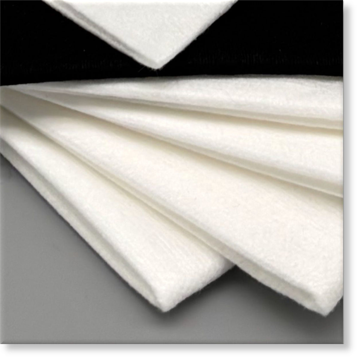 Tunika Disposable Salon Towels Image showing a closeup of mix fanned out stack of Black and White sample towels in various sizes for a Sample Pack