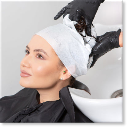 Image of a young woman having her hair wrapped in a disposable towel after washing her hair