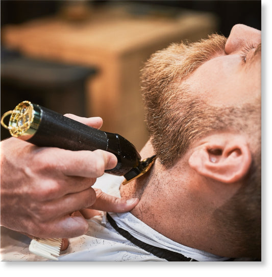 Close-up of professional barber trimming client's beard. Male hairdresser serving client with thin beard by clipper. Isolated photo of man getting his haircut done.